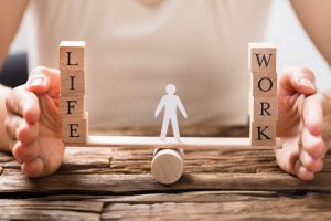 human figure on seasaw with blocks saying Life on one side and Work on the other side